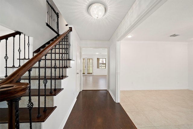 entrance foyer featuring visible vents, wood finished floors, baseboards, and ornamental molding