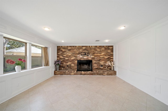 unfurnished living room featuring light tile patterned floors, a brick fireplace, crown molding, and a decorative wall