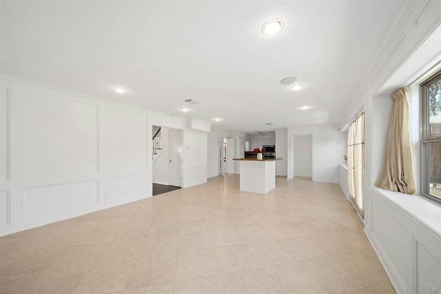 unfurnished living room featuring a decorative wall, recessed lighting, and stairway