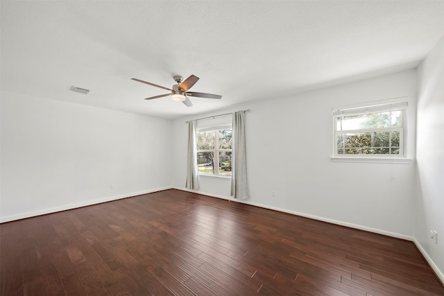 unfurnished room with baseboards, visible vents, dark wood-style flooring, and ceiling fan