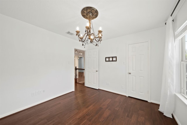 spare room with an inviting chandelier, baseboards, visible vents, and dark wood-style flooring