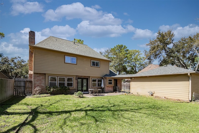 back of house with brick siding, a lawn, a chimney, a fenced backyard, and a patio