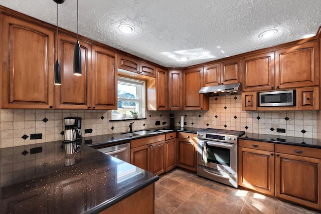 kitchen featuring a sink, brown cabinets, under cabinet range hood, and stainless steel appliances