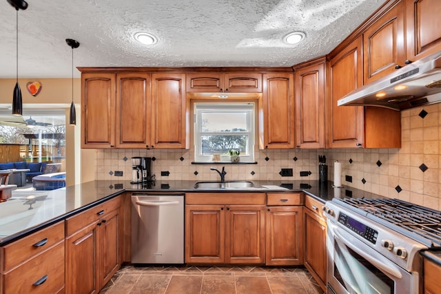 kitchen with a sink, dark countertops, appliances with stainless steel finishes, and under cabinet range hood