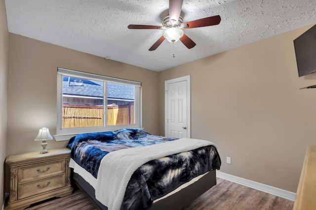 bedroom with a ceiling fan, wood finished floors, baseboards, and a textured ceiling