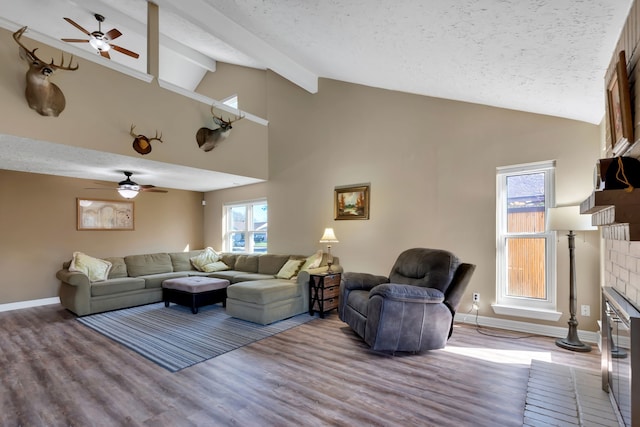 living room featuring beamed ceiling, a textured ceiling, a brick fireplace, and wood finished floors