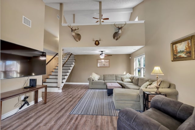 living room featuring visible vents, high vaulted ceiling, wood finished floors, stairway, and ceiling fan