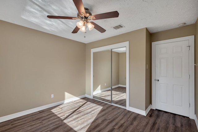 unfurnished bedroom with wood finished floors, visible vents, baseboards, a closet, and a textured ceiling