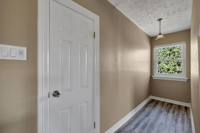 interior space with baseboards, a textured ceiling, and wood finished floors