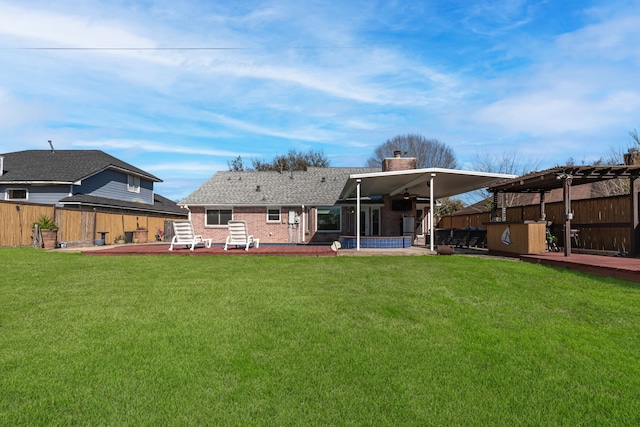 rear view of property with a patio, a yard, a fenced backyard, a chimney, and brick siding