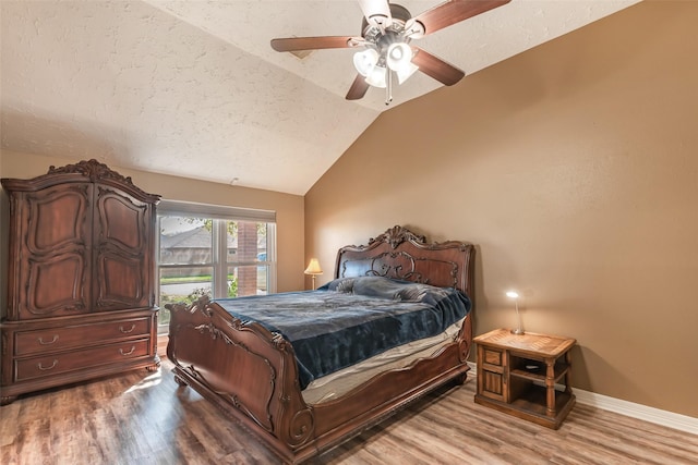 bedroom with baseboards, lofted ceiling, wood finished floors, a textured ceiling, and a ceiling fan