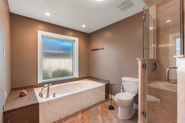 bathroom featuring visible vents, a shower stall, toilet, a garden tub, and a textured ceiling