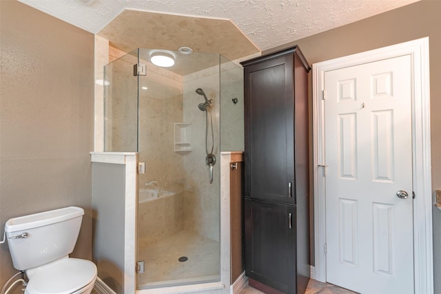 bathroom with a shower stall, a textured ceiling, and toilet