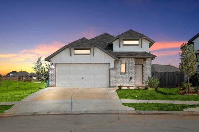 view of front of home with brick siding, fence, a garage, a yard, and driveway