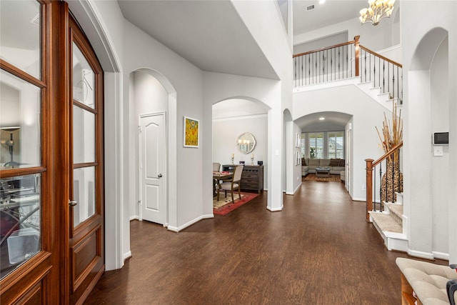 entrance foyer with a notable chandelier, dark wood-style floors, baseboards, a towering ceiling, and stairs