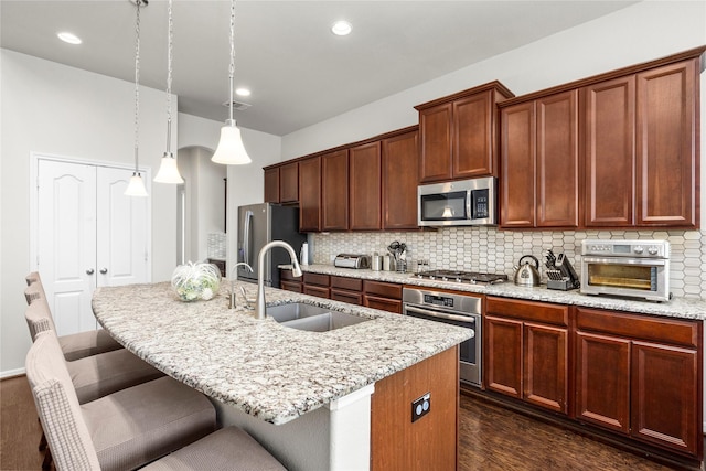 kitchen featuring a sink, stainless steel appliances, a kitchen island with sink, and decorative backsplash