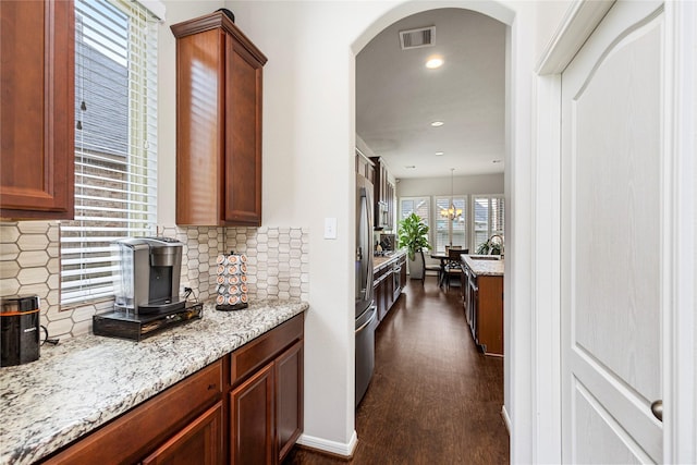 kitchen with tasteful backsplash, visible vents, dark wood-type flooring, and light stone countertops