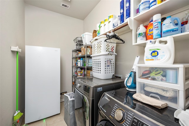 laundry room featuring washer and clothes dryer, laundry area, tile patterned flooring, and visible vents