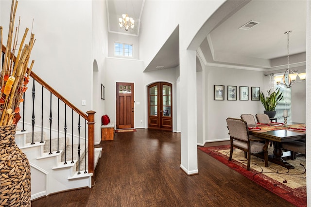 foyer entrance with visible vents, a notable chandelier, wood finished floors, arched walkways, and stairs