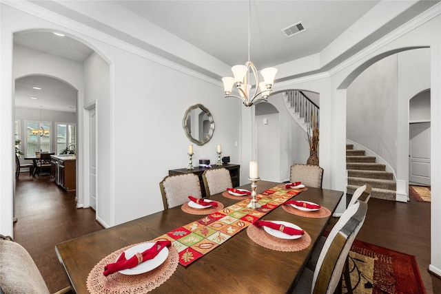 dining room featuring dark wood-style floors, visible vents, an inviting chandelier, arched walkways, and stairs