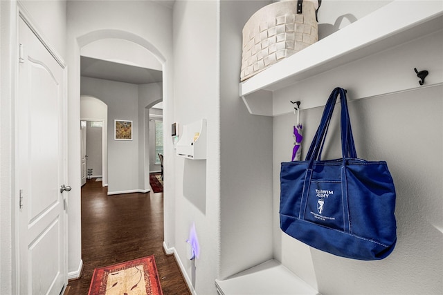 mudroom with baseboards, arched walkways, and wood finished floors