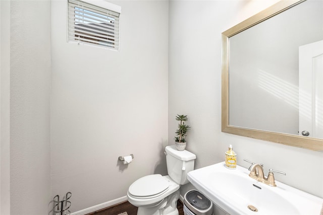 bathroom featuring a sink, baseboards, toilet, and wood finished floors