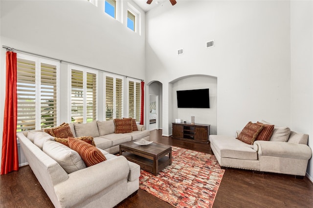 living room featuring visible vents, arched walkways, dark wood finished floors, and a ceiling fan