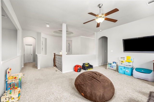 recreation room featuring carpet floors, visible vents, arched walkways, and ceiling fan