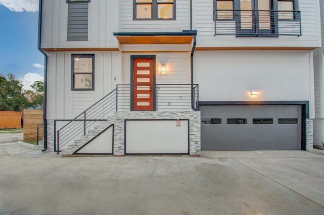 exterior space featuring stone siding, board and batten siding, an attached garage, and concrete driveway