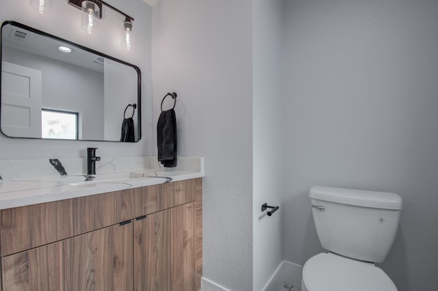 half bathroom featuring visible vents, toilet, and vanity