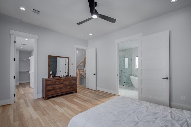 bedroom with visible vents, baseboards, ensuite bath, light wood-style floors, and a walk in closet