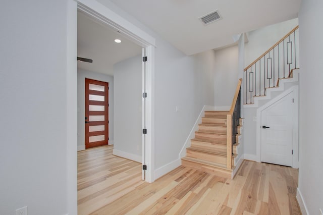 stairs featuring wood finished floors, visible vents, and baseboards