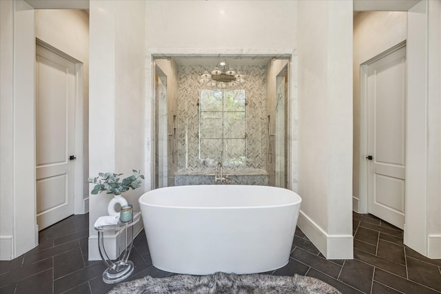 bathroom with tile patterned flooring, a shower stall, a freestanding bath, and baseboards