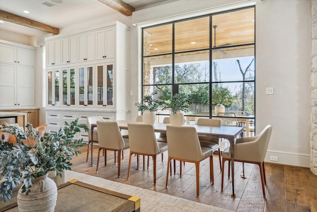 dining space with beamed ceiling, baseboards, and wood-type flooring