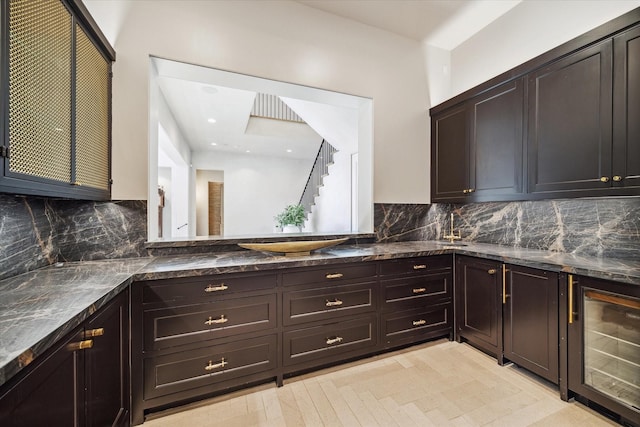 kitchen with dark stone countertops, wine cooler, dark brown cabinets, and backsplash