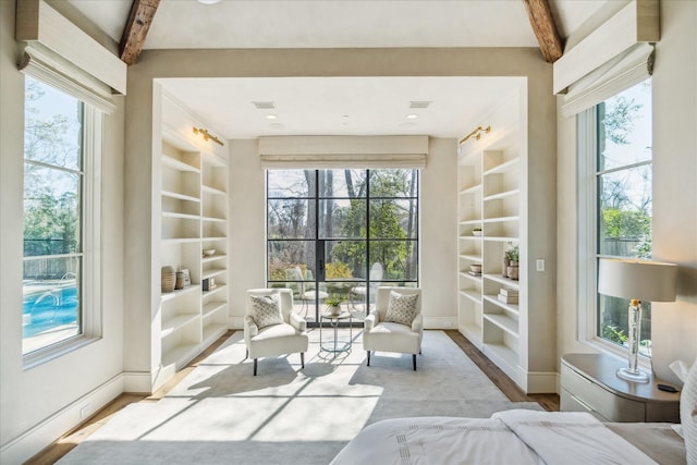 sitting room featuring baseboards, built in shelves, and plenty of natural light