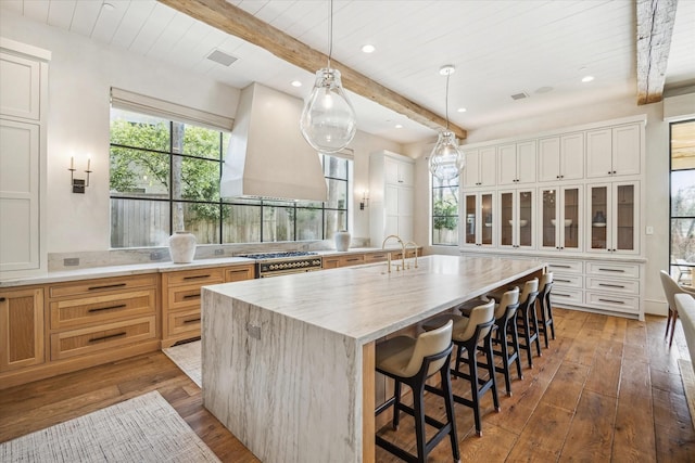 kitchen featuring beamed ceiling, double oven range, premium range hood, and a sink