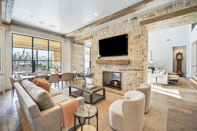 living room featuring hardwood / wood-style floors, recessed lighting, a stone fireplace, wooden ceiling, and beamed ceiling