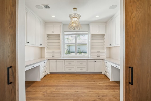 kitchen featuring built in desk, white cabinetry, and visible vents