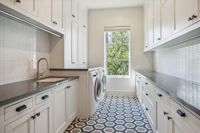 laundry room featuring tile patterned floors, washer and clothes dryer, a sink, cabinet space, and baseboards