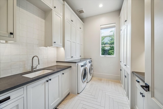 laundry area with a sink, recessed lighting, cabinet space, baseboards, and washing machine and clothes dryer