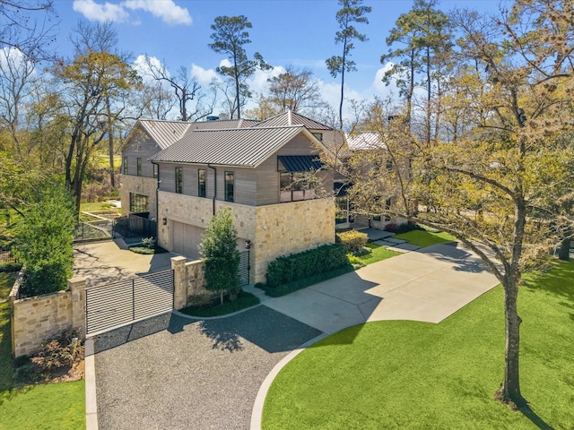 exterior space with driveway, a standing seam roof, stone siding, fence, and metal roof