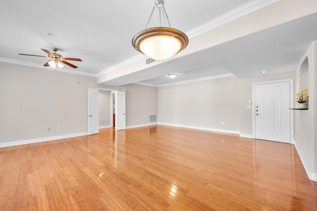 spare room featuring light wood finished floors, visible vents, crown molding, ceiling fan, and baseboards