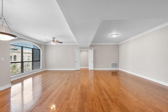 unfurnished living room with a ceiling fan, visible vents, baseboards, light wood-style floors, and crown molding