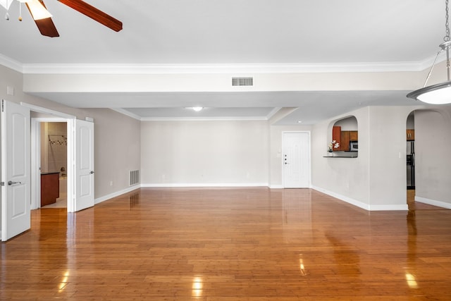 unfurnished living room with ornamental molding, wood finished floors, visible vents, and baseboards