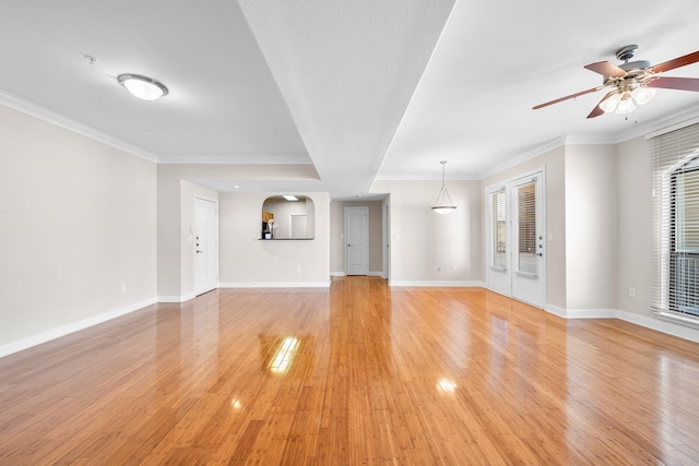 unfurnished living room with light wood-type flooring, baseboards, ornamental molding, and a ceiling fan