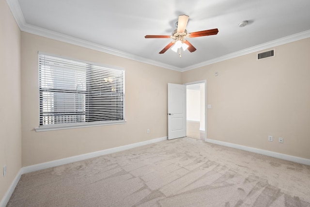 carpeted empty room with visible vents, ceiling fan, crown molding, and baseboards