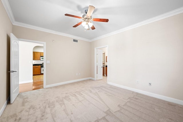 unfurnished bedroom with visible vents, light carpet, arched walkways, crown molding, and baseboards