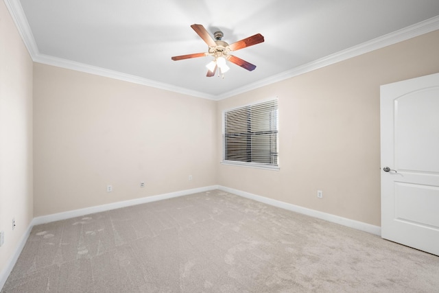 carpeted spare room with crown molding, a ceiling fan, and baseboards