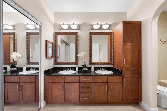 full bath with double vanity, toilet, and a sink